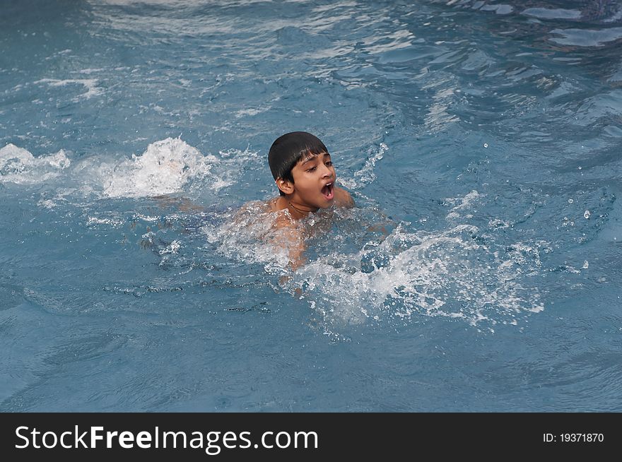 An handsome young indian kid swimming in the pool