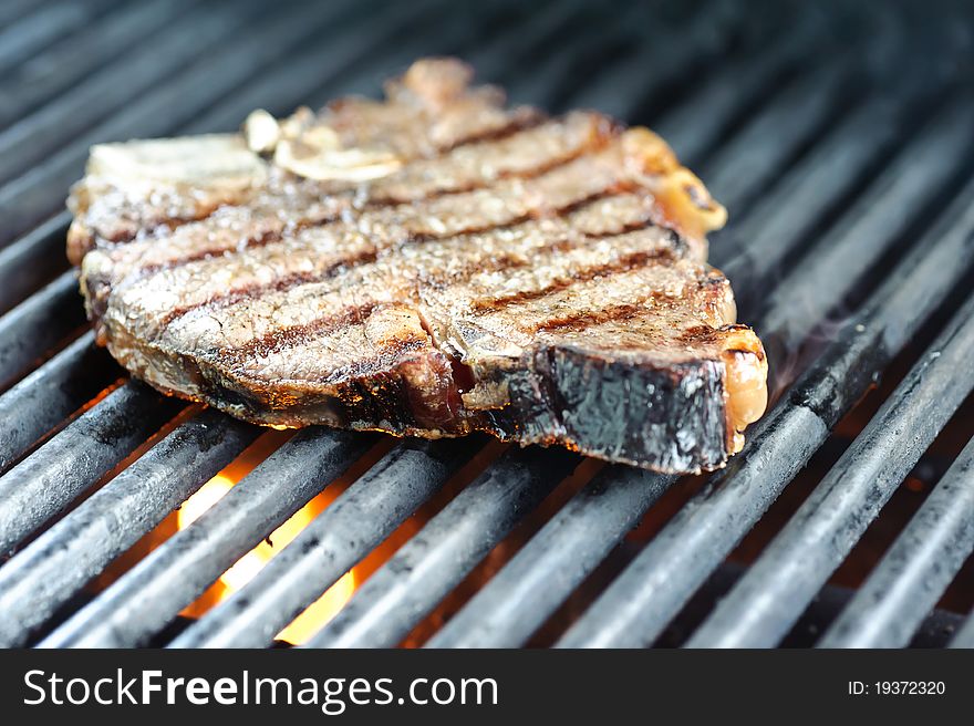 Steak on the grill with flames under the griddle