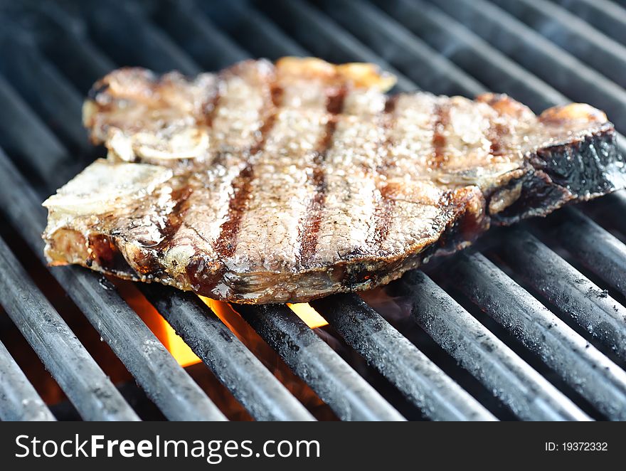 Steak on the grill with flames under the griddle