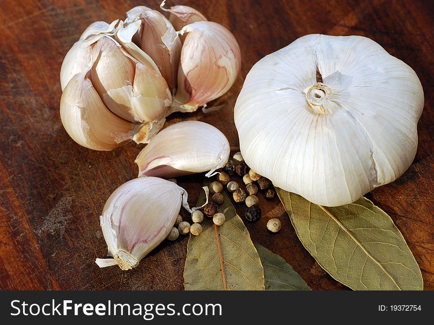 Garlic bulbs and cloves closeup with spices on wooden cutting board. Garlic bulbs and cloves closeup with spices on wooden cutting board