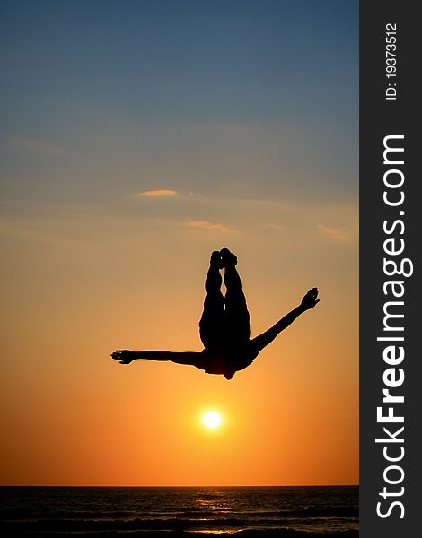 Silhouette of man jumping in sunset at beach