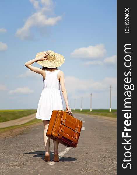 Lonely girl with suitcase at country road. Ukraine.