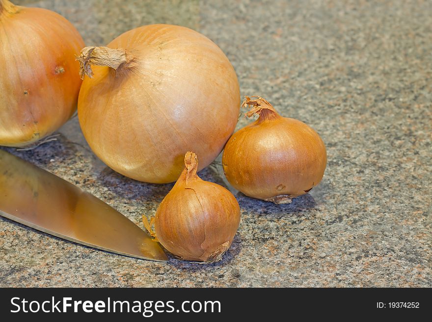 Onions with knife on kitchen worktop. Onions with knife on kitchen worktop