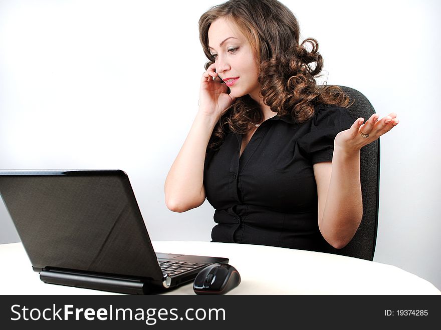 A beautiful caucasian businesswoman talking on the phone while working on her laptop