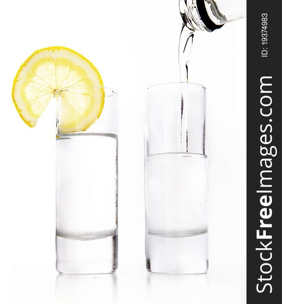 Two wine-glasses of vodka and lemon on a white background. Two wine-glasses of vodka and lemon on a white background
