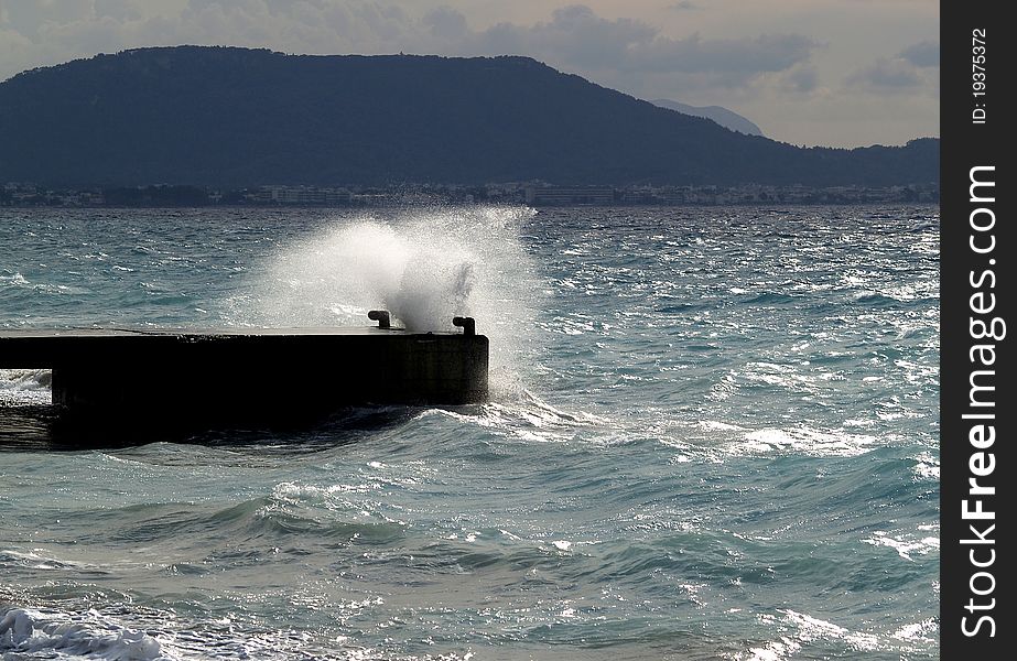 Wave breaking against stone mooring. Beach on the Rhodes island, Greece