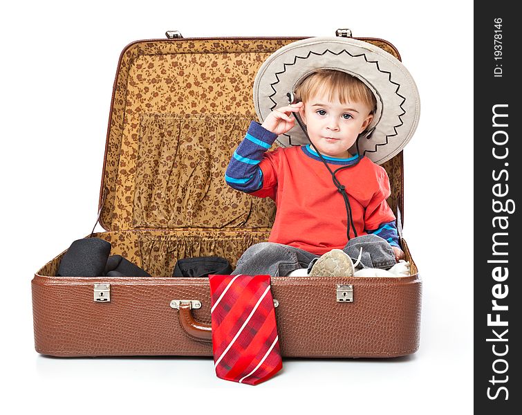 A funny boy with sombrero is sitting in the suitcase. Isolated on a white background. A funny boy with sombrero is sitting in the suitcase. Isolated on a white background