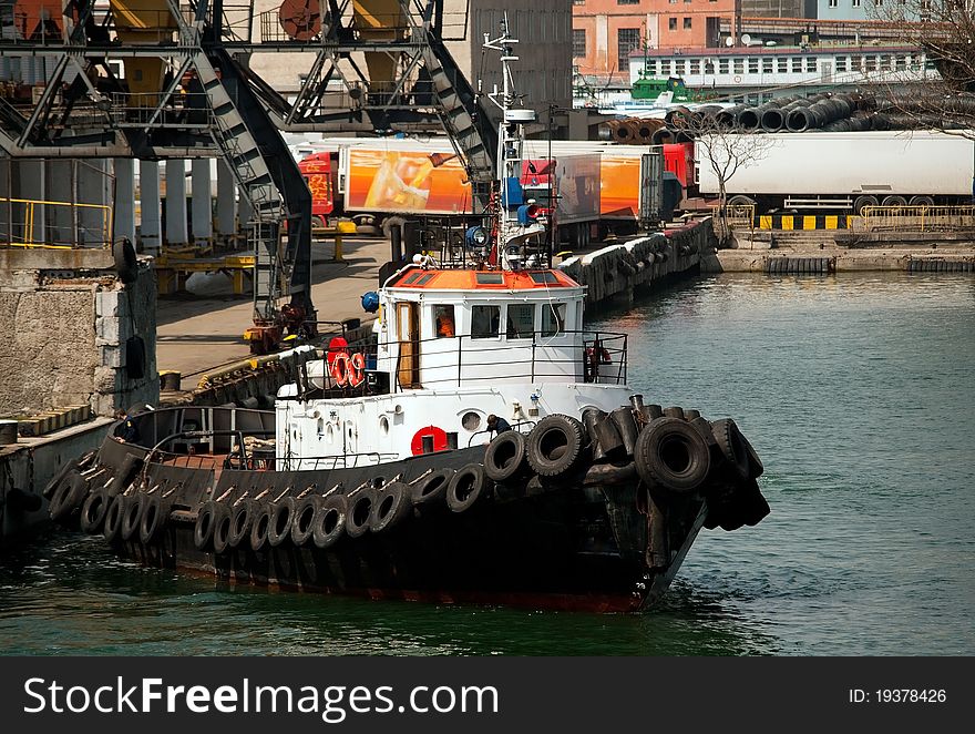 Tug boat in the port and cranes in the background