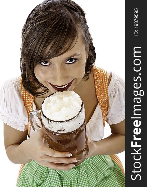 Beautiful young woman with dirndl drinks Oktoberfest beer stein. Isolated on white background.