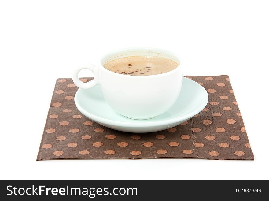 A cup of coffee on a brown dotted napkin isolated over white background. A cup of coffee on a brown dotted napkin isolated over white background