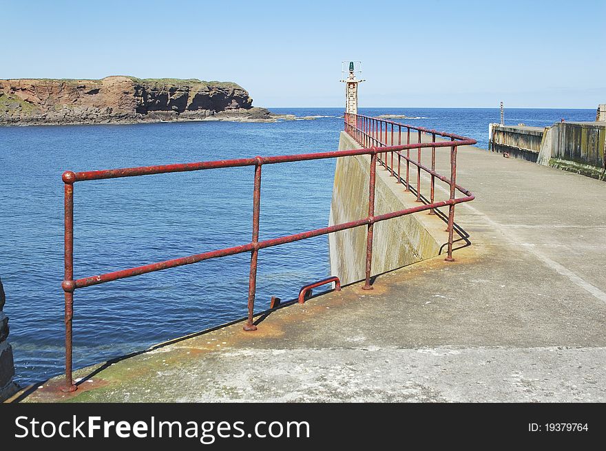 View of Eyemouth harbour entrance looking out to sea with cliffs and rocks. View of Eyemouth harbour entrance looking out to sea with cliffs and rocks