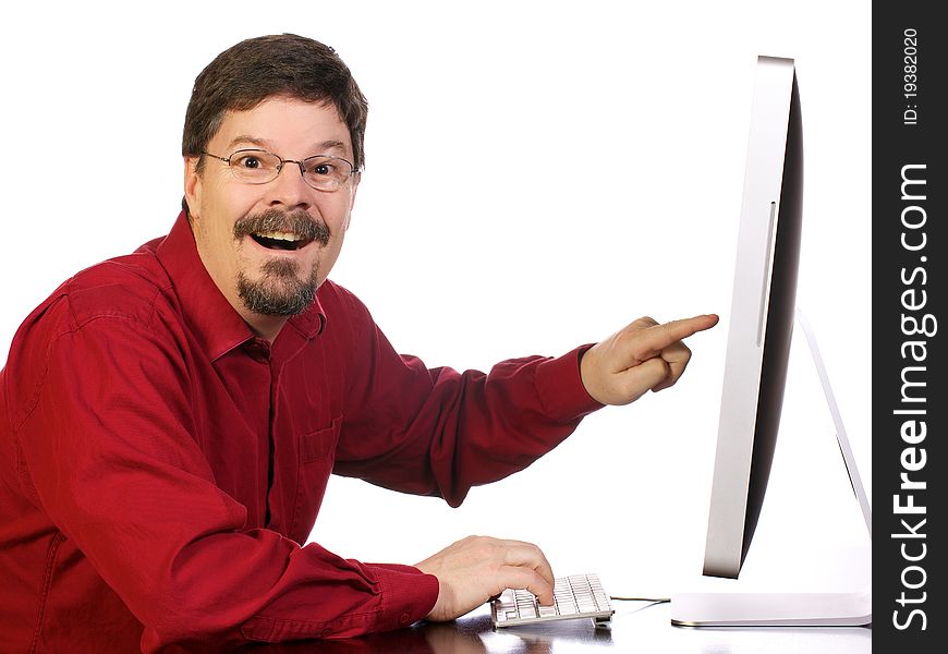 Casually dressed mature business man works and his computer while excitedly pointing out something important on the computer. Casually dressed mature business man works and his computer while excitedly pointing out something important on the computer