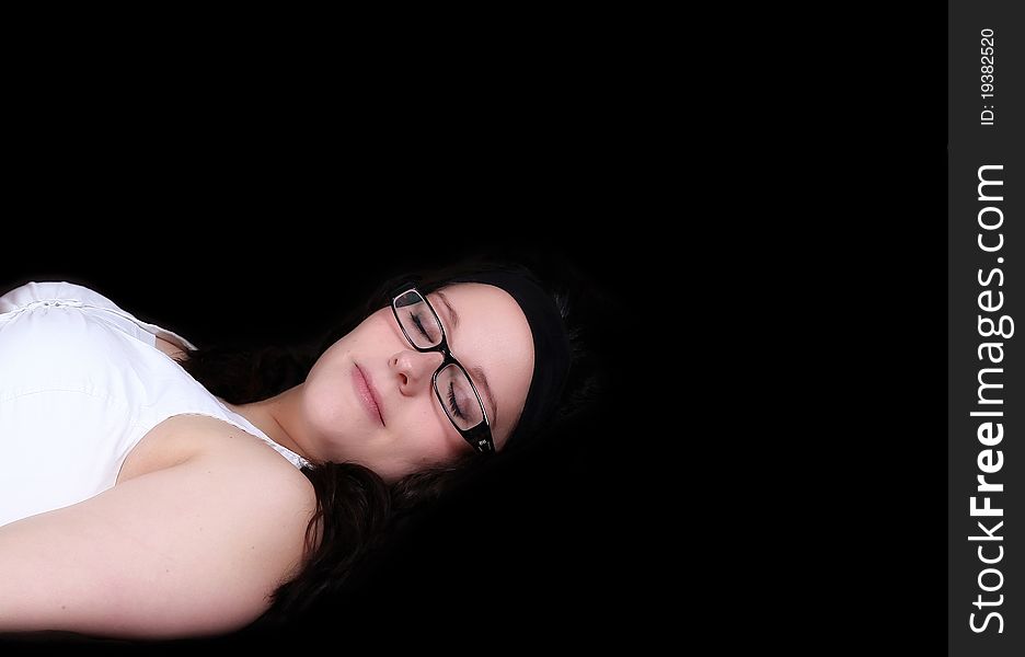 Beautiful young woman laying with eyes closed isolated on black. Beautiful young woman laying with eyes closed isolated on black
