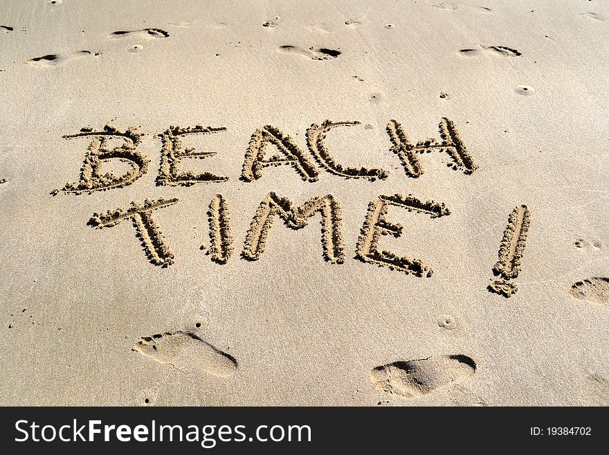 Beach Time carved in the sand with barefoot prints around it. Beach Time carved in the sand with barefoot prints around it.