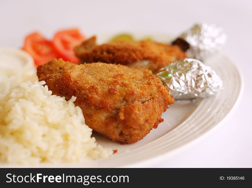 Chicken drumsticks and rice vegetables on white dish. Chicken drumsticks and rice vegetables on white dish