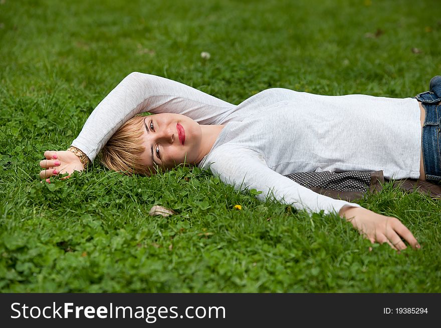 Pretty woman laying on the grass with hands behind head