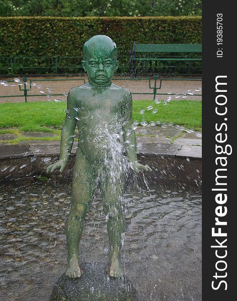 Statue of crying boy in fontain in city park of Bergen, Norway