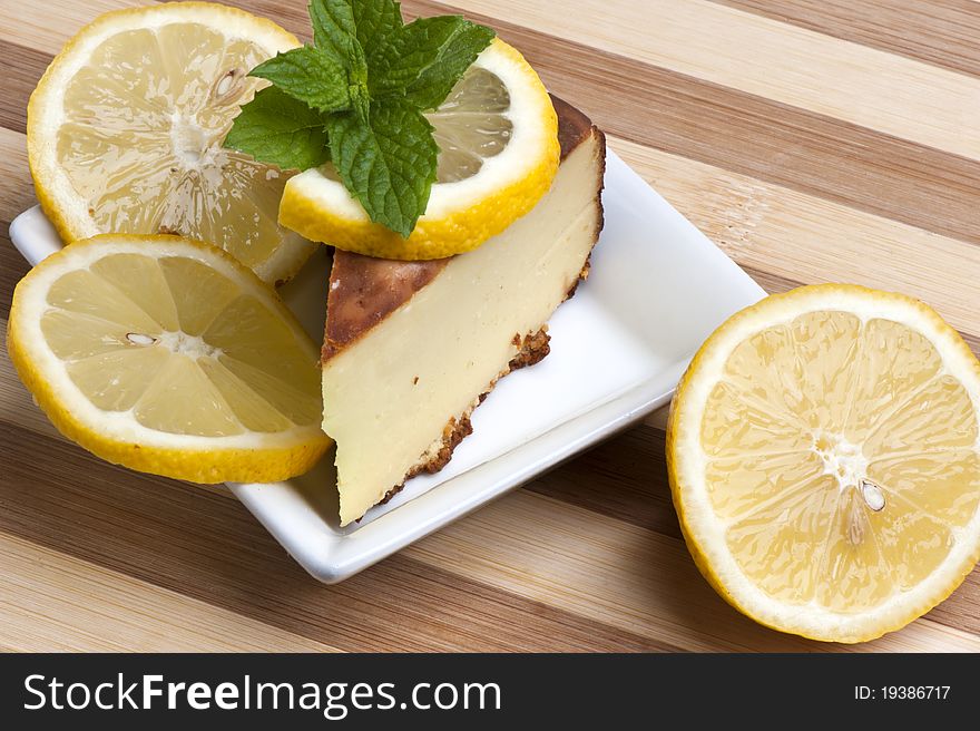 A piece of lemon cake decorated with lemon slices and mint leaves