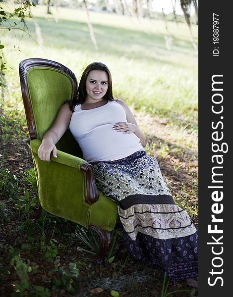 Pregnant woman sitting outside in vintage chair.