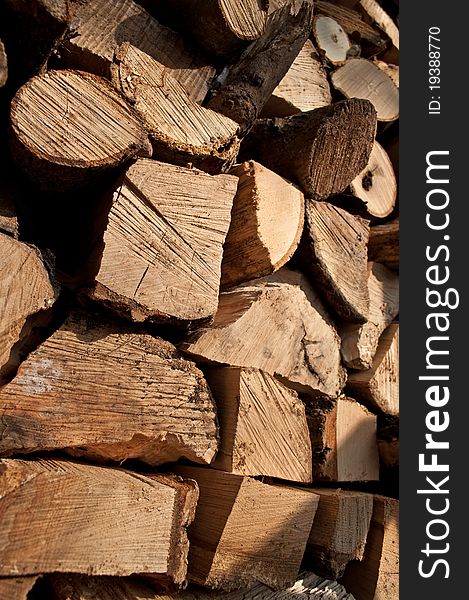 Close up on the ends of a large group of stacked, chopped rustic fire wood in outdoor setting with full sunlight. Close up on the ends of a large group of stacked, chopped rustic fire wood in outdoor setting with full sunlight