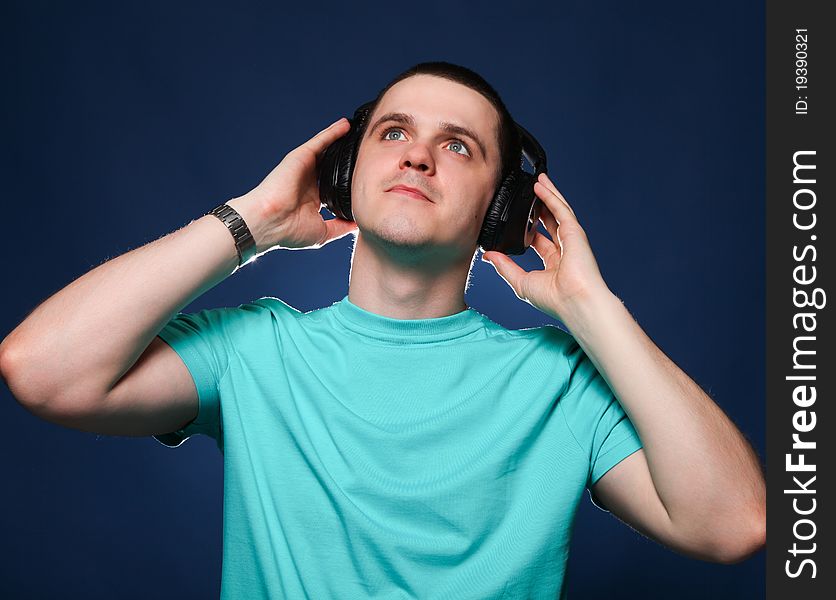 Man with headphones listening music at blue background