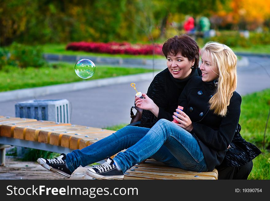 Teenage daughter blow bubbles, her mom was watching her. Teenage daughter blow bubbles, her mom was watching her