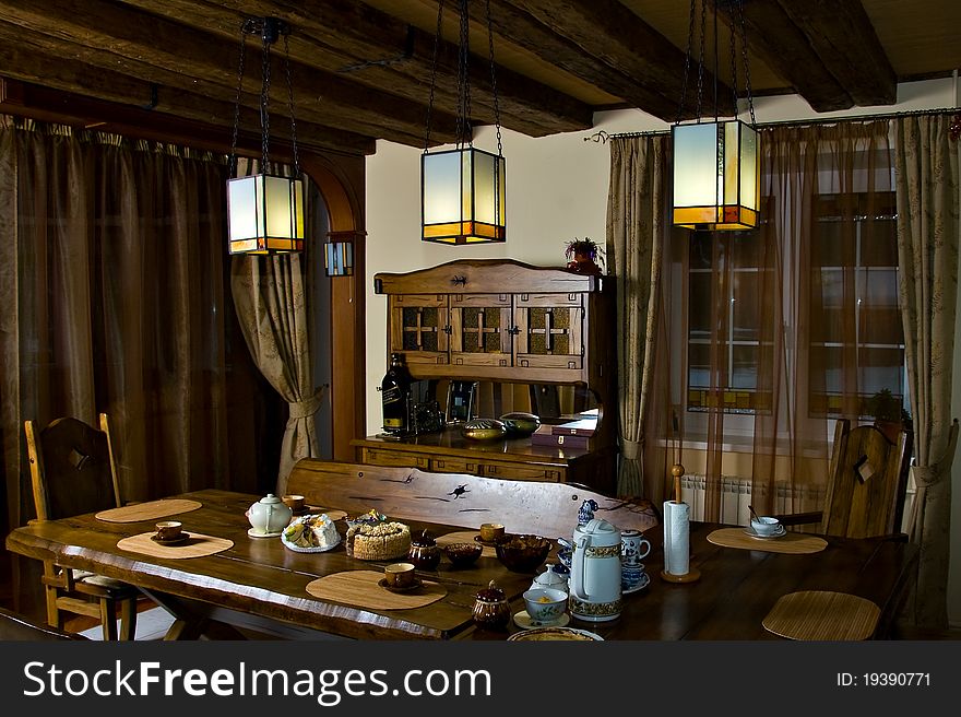The interior dining room in the cottage - a wooden structure protected by a tree shaded lamps. The interior dining room in the cottage - a wooden structure protected by a tree shaded lamps