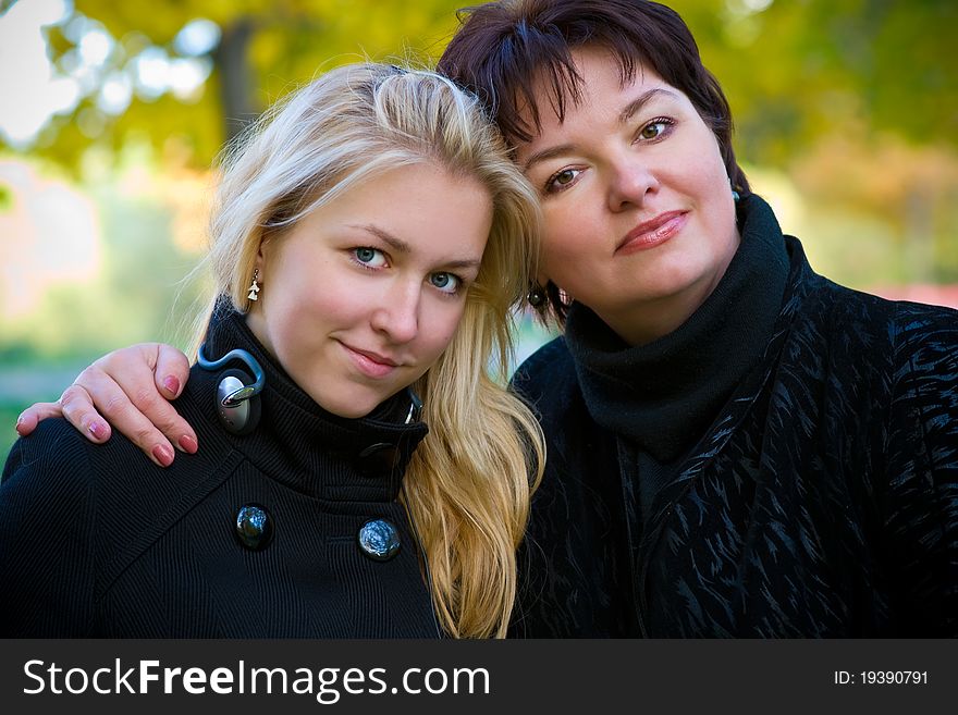 Mom and teen girl with long blond hair standing arm in arm. Mom and teen girl with long blond hair standing arm in arm