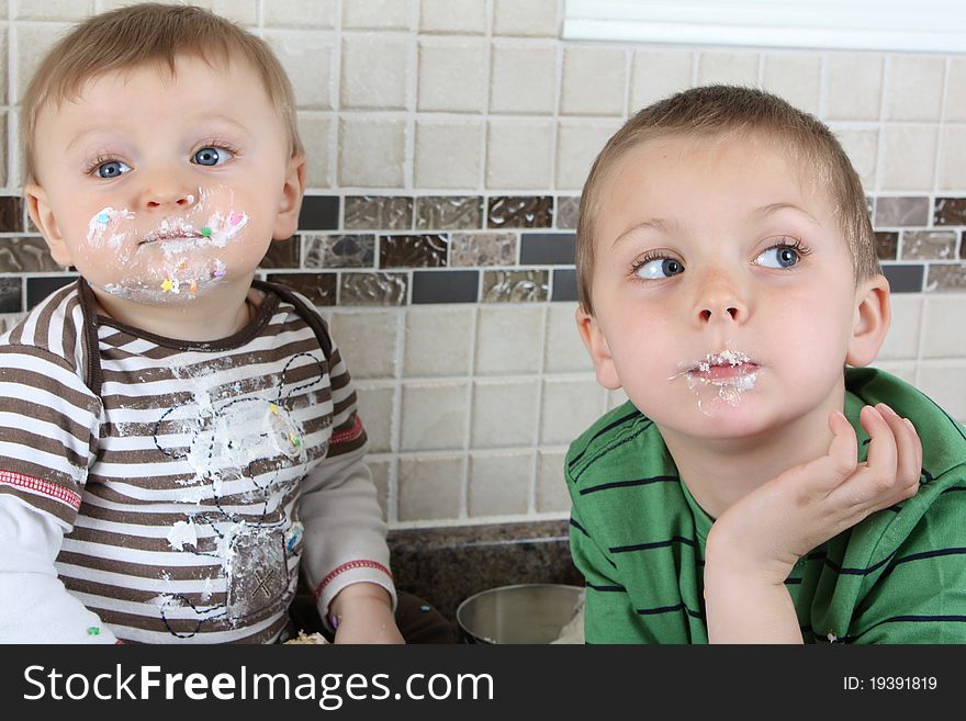 Brothers on kitchen counter eating icing sugar. Brothers on kitchen counter eating icing sugar