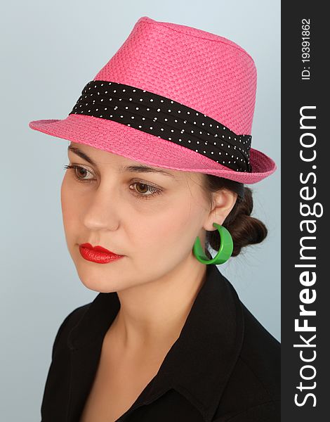 Brunette female wearing a pink hat and green earrings