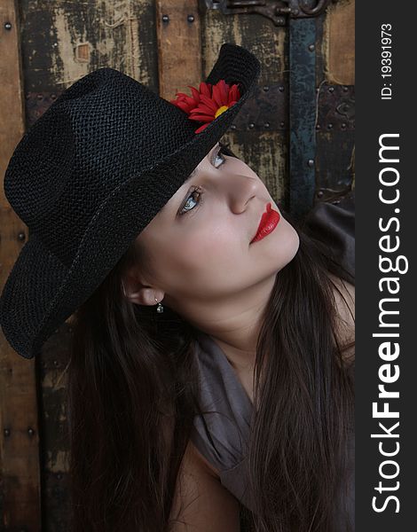 Brunette female with hat in front of antique trunk. Brunette female with hat in front of antique trunk