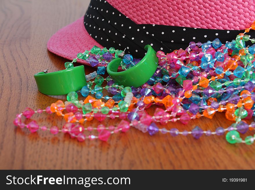 Costume Jewelery and pink hat on wooden table. Costume Jewelery and pink hat on wooden table