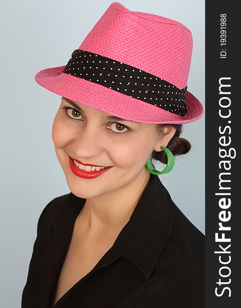 Brunette female wearing a pink hat and green earrings