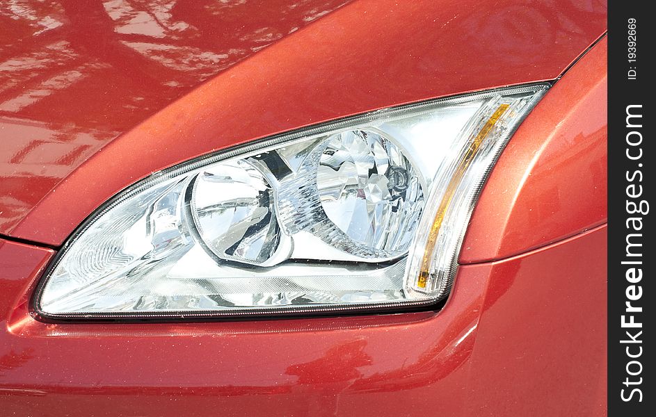 Red car headlight close up shot. Red car headlight close up shot