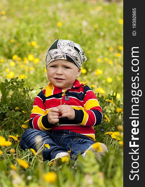Little boy sitting on green grass in the reflection