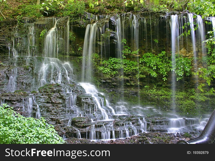 A stream cascades below a gentle waterfall. A stream cascades below a gentle waterfall