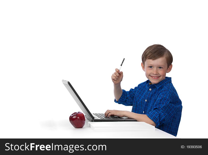Seven-year-old cute caucasian boy working on laptop, raising his hand, holding pen on white background, smiling and looking up. Seven-year-old cute caucasian boy working on laptop, raising his hand, holding pen on white background, smiling and looking up