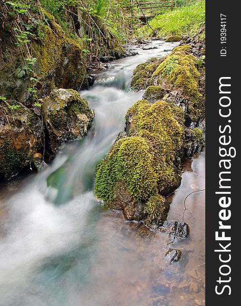 Stream between stones in green forest landscape. Stream between stones in green forest landscape