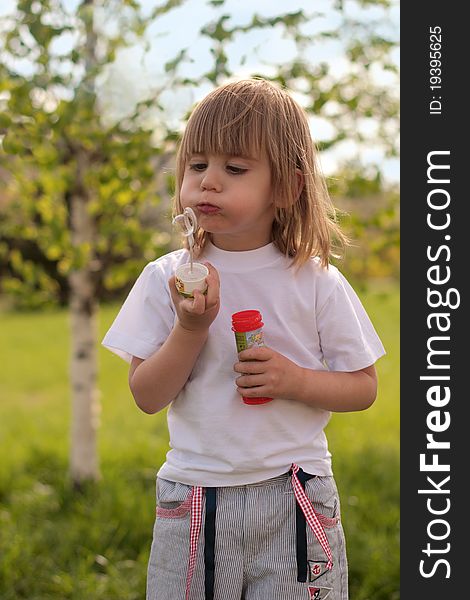 Cute funny two years girl blowing soap bubbles in the park. Cute funny two years girl blowing soap bubbles in the park