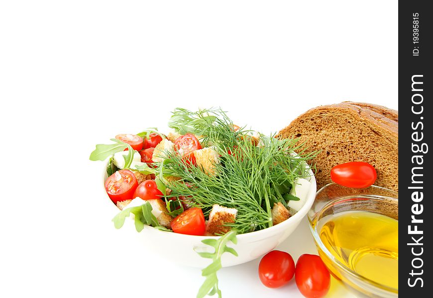 Mixed salad with cherry tomatoes, arugula, mozzarella, a loaf of rye bread and olive oil on white background. Mixed salad with cherry tomatoes, arugula, mozzarella, a loaf of rye bread and olive oil on white background