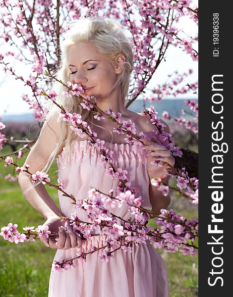 Young pretty blond woman in blooming garden