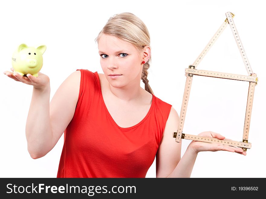 Young woman with folding rule as a house symbol and piggy bank before white background. Young woman with folding rule as a house symbol and piggy bank before white background