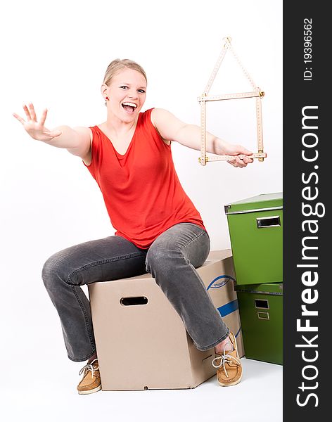 Young woman with a house symbol sits on moving box