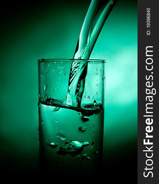 Glass beaker with water on a green background