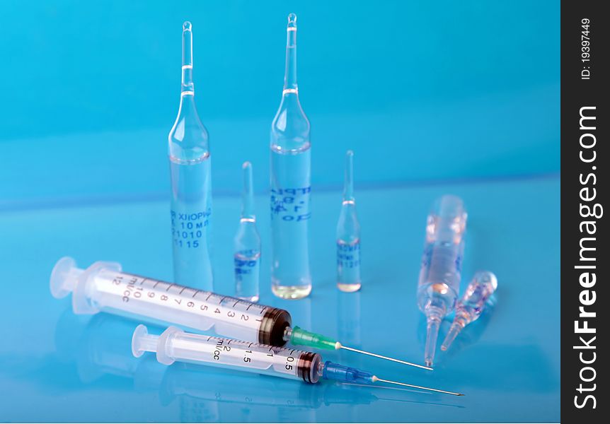 Vials and syringe on the blue background. Vials and syringe on the blue background.