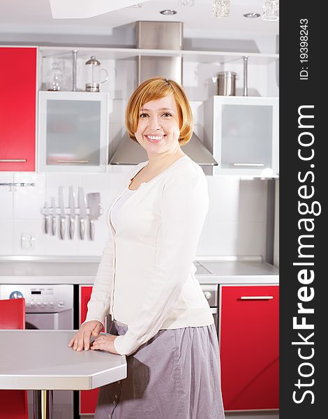 Smiling beautiful young woman standing at kitchen