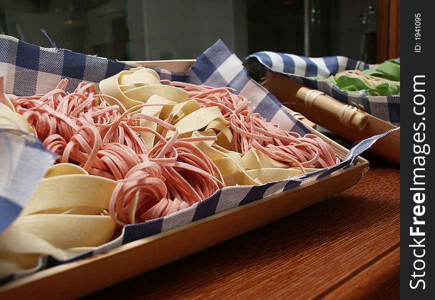 Red and white spaghetti in the wooden plate on the table