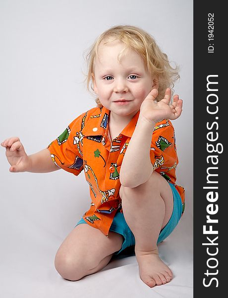 Sitting smiling little boy in orange shirt. Sitting smiling little boy in orange shirt