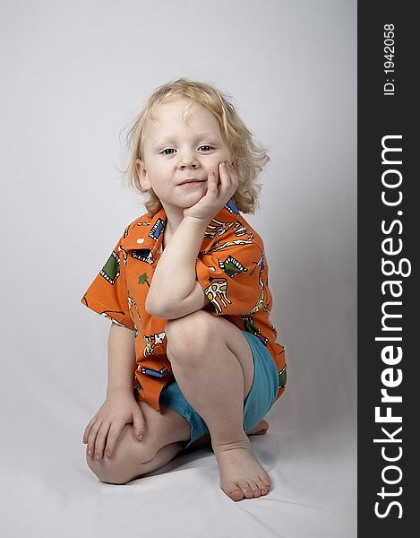 Sitting smiling little boy in orange shirt. Sitting smiling little boy in orange shirt