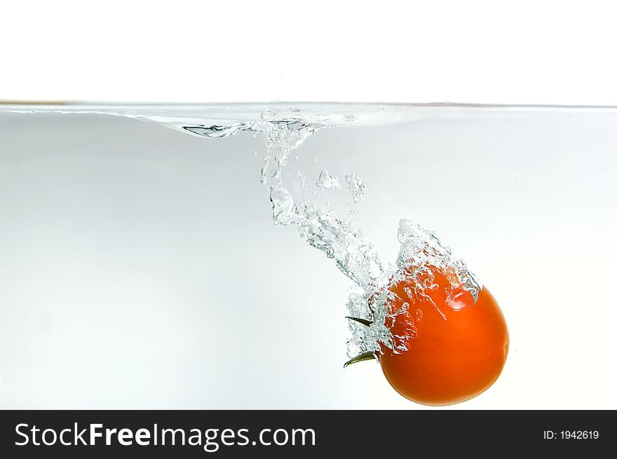 Dropping a tomato in water, isolated on background